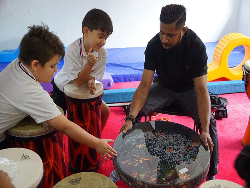 image of MSIS teacher with students using drumming therapy