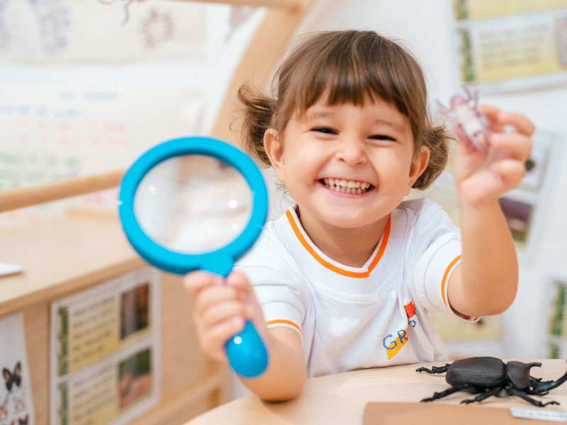 The Grange preschool student with magnifying glass