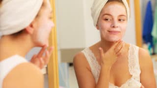 image of woman applying skincare and looking in the mirror