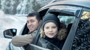 Boy and father in car driving during winter