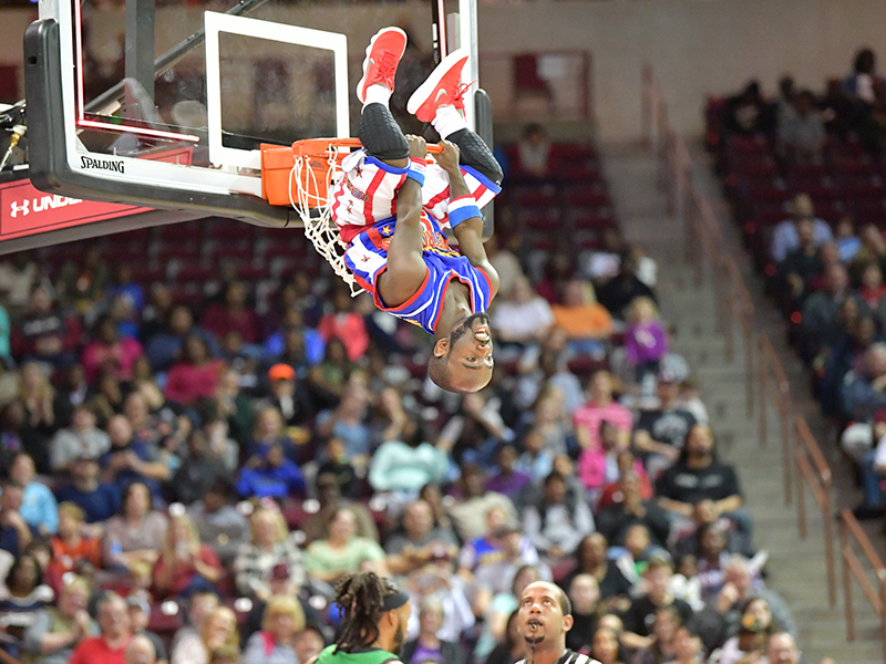 Harlem Globetrotters hanging from basketball hoop