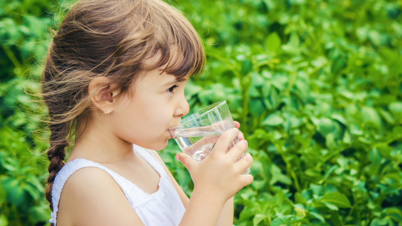 Girl drinking glass of water outdoors