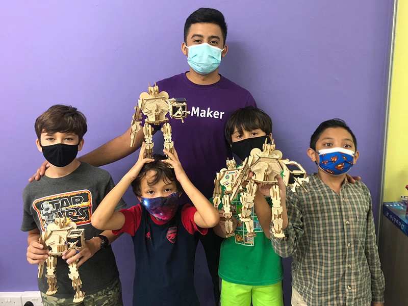Maker.sg holiday camps in Singapore group of boys and instructor with wooden robots