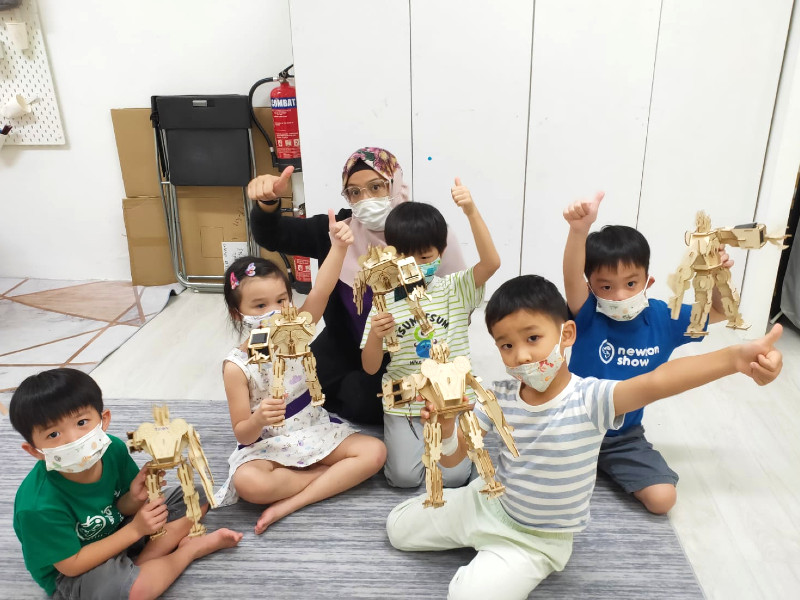 Maker.sg year-end camps group holding wooden robots