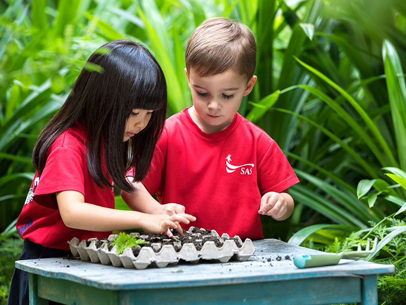Singapore American School two kids outdoors planting seedlings preschool learning