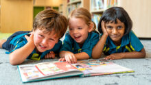 AIS Early Learning Village students reading a book together